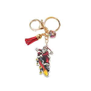 Cartoon Santa Claus on skateboard keychain with red tassel and colorful star bead