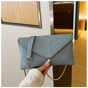 Detail of blue-grey envelope bag with cross-grain texture and gold metal chain strap