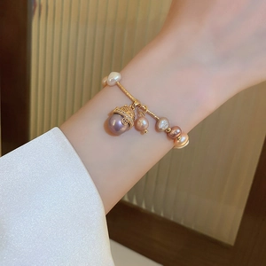 Close-up of a gold bracelet with colorful freshwater pearls and lucky cat pendant