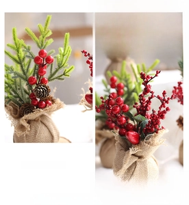 Close-up of a mini Christmas tree with red berries, pine cones and burlap base decor