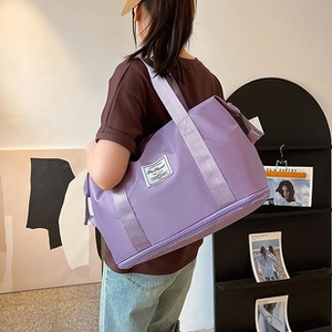 Dettaglio della borsa a secchiello viola intrecciata con ampia tracolla e tessuto