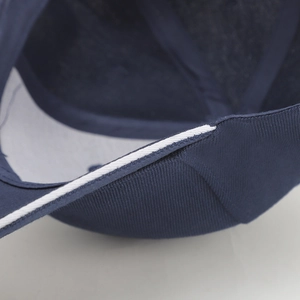 Detail of navy blue twill fabric baseball cap with white edge trim and stitching
