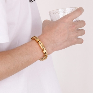 Detailed close-up of golden paperclip link chain bracelet on male model wrist