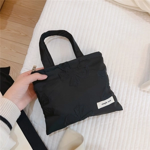 Close-up of black jacquard handbag featuring a bow embroidery and simple wish label