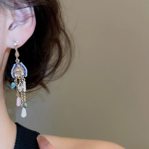 Détail de boucles d'oreilles franges de luxe avec cristaux, perles et perles colorées