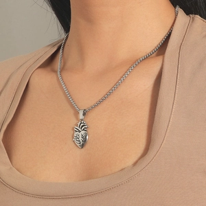 Primo piano di una collana con ciondolo a cuore anatomico in argento su modella
