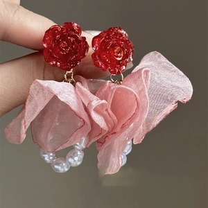 Detailed macro view of handmade red rose earrings with fabric petals and white pearls