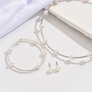 Detail of silver bridal jewelry set featuring pearls and rhinestones on white silk