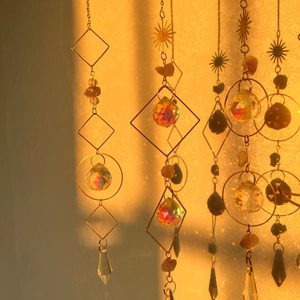 Detail of bohemian crystal wind chimes with gold frames and amber stones in warm light