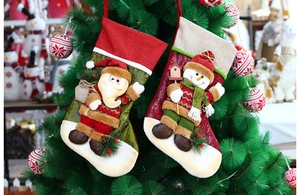 Detail of hanging Christmas stockings with 3D Santa and Snowman plush on a decorated tree