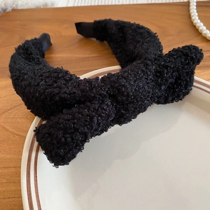 Close-up of black plush bow headband made of sherpa fleece on a decorative white plate