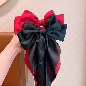 Detail showing oversized red and black satin bow hair clips with a silky smooth finish