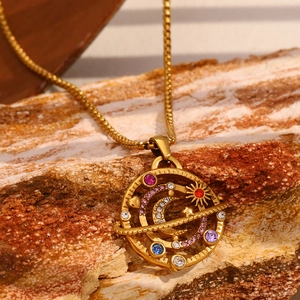 Detailed macro view of 18K gold plated compass pendant with colorful crystals on a rock