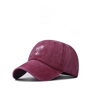 Détail de la broderie cocotier blanc sur une casquette en coton lavé de couleur bordeaux