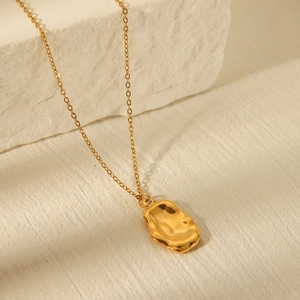 Close-up of golden irregular textured pendant necklace on elegant stone background