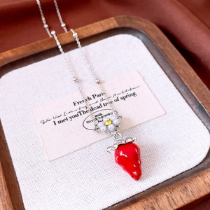 Close-up of red strawberry pendant necklace with pearl flower and silver bead chain