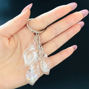 Detailed macro view of resin conch charms with sequins and pearls on a keychain