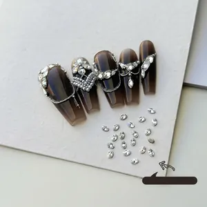Close-up of 2x3mm oval white nail rhinestones shown on a dark nail tip for manicure