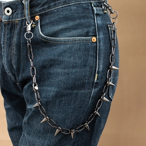 Detail view of punk style jean chain with metal spikes and hooks on blue denim jeans