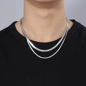 Detail of layered silver snake bone chains on model neck with minimalist metallic finish