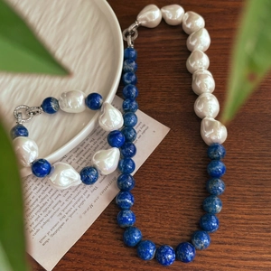 Baroque pearl and lapis lazuli jewelry set with vintage metal clasp on wooden desk
