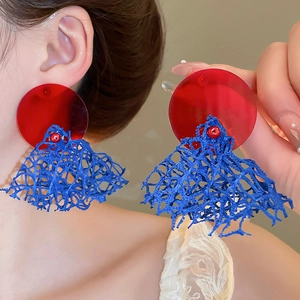 Gros plan sur des boucles d'oreilles en maille rouge et bleue avec disques acryliques