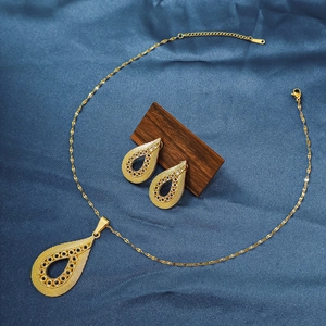 Detail of gold necklace and teardrop earrings set with black gemstones on blue silk
