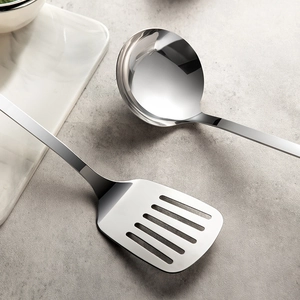 Polished stainless steel soup ladle and slotted spatula set on minimalist background