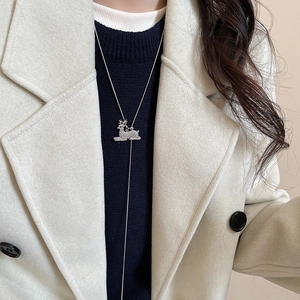 Detailed view of silver reindeer pendant with micro-inlaid diamonds on a winter sweater