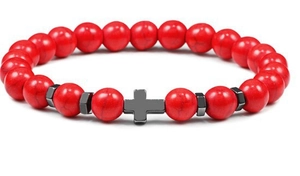 Macro detail of men's beaded bracelet featuring red marble beads and black metal cross