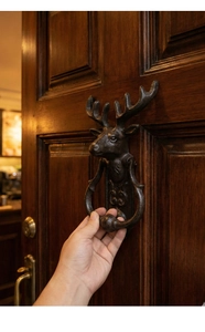 Close-up of vintage cast iron deer head door knocker installed on a wooden door