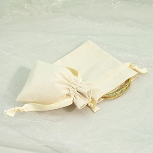 Macro view of a gold bracelet inside a beige cotton jewelry drawstring pouch