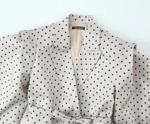 Gros plan détaillé du revers du blazer beige et des coutures avec motif à pois noirs