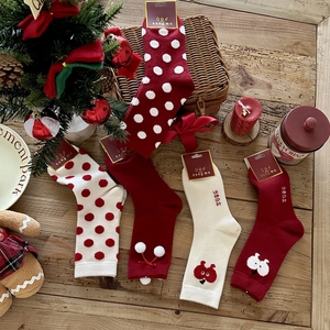 Flat lay of festive thick Christmas socks with plush pompoms on a rustic wooden background