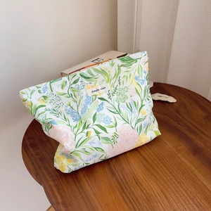 Detail of floral cotton makeup bag with simple wish label on rustic wooden table