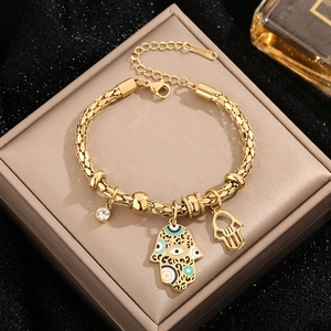 Golden Hamsa hand charm bracelet with blue evil eye on professional jewelry box