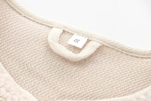 Macro detail of white waffle knit texture and size label on the teddy fleece jacket