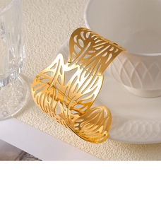 Macro detail of gold-plated cutout bangle showing intricate leaf textures and organic lines