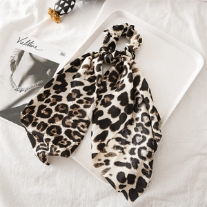 Close-up of leopard print satin hair scrunchie with long ribbon on a white display