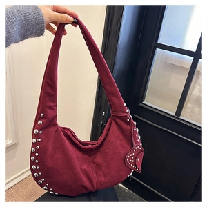 Détail du sac à bandoulière en daim bordeaux avec rivets et breloque en cœur