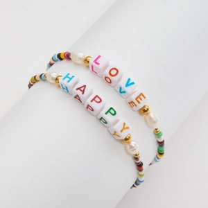 Detail of colorful beaded bracelets set with LOVE and HAPPY letter charms on a display stand