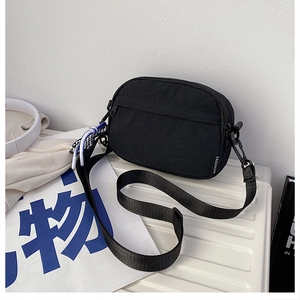 Détail d'un petit sac bandoulière en nylon noir avec fermeture éclair et étiquette