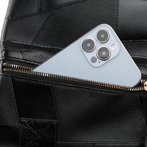 Detail of black leather backpack showing a functional zipper pocket with a phone inside
