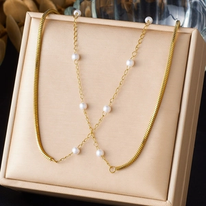 Gold snake chain and pearl layered necklace displayed on a luxury champagne jewelry box