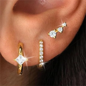 Close-up of a three-piece gold earring set with cubic zirconia on a model's ear