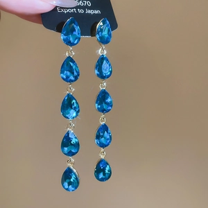 Blue drop-shaped crystal fringe earrings with gold finish and five-stone waterfall design