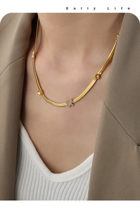 Détail d'un collier pendentif papillon doré porté sur un tailleur élégant