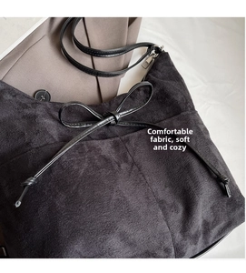 Detailed macro view of soft charcoal suede fabric and bow detail on the hobo bucket bag