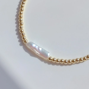 Bohemian gold plated necklace with irregular natural freshwater baroque pearl on white background