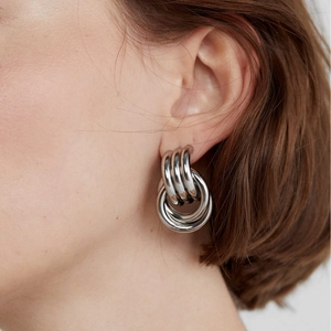 Macro view of multi-layered silver polished hoop earrings on model with high gloss finish